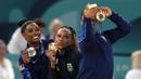 Pesenam Amerika Serikat  Jordan Chiles (kanan) melakukan swafoto bersama pesenam Brasil Rebeca Andrade (tengah), dan pesenam Amerika Serikat Simone Biles (kiri) pada cabang olahraga senam Olimpiade Paris 2024 di Bercy Arena, Paris, Prancis, Senin (05/08/2024). (AP Photo/Francisco Seco)