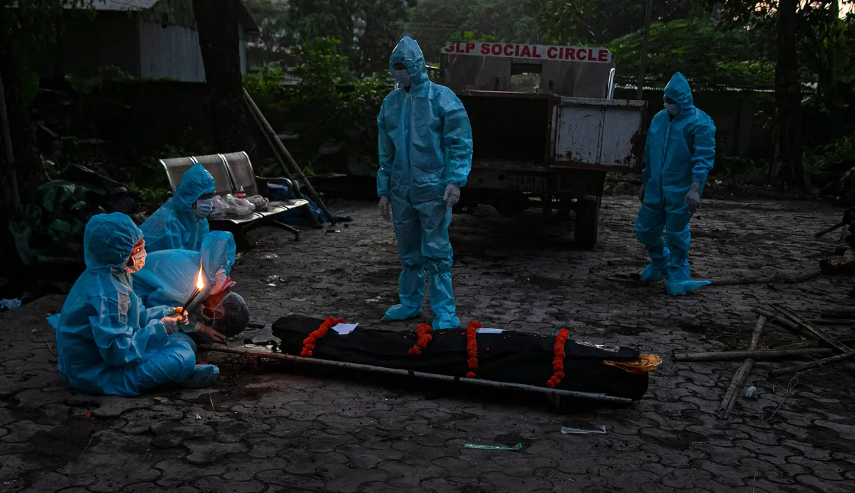 Kerabat dengan mengenakan alat pelindung diri melakukan ritual selama kremasi seseorang yang meninggal karena virus corona COVID-19 di Gauhati, India pada 28 September 2020. (AP Photo/Anupam Nath)