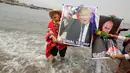 Dukun Peru menunjukkan poster Donald Trump dan Vladimir Putrin saat menggelar ritual di Pantai Agua Dulce di Lima, Peru, (29/12). Pada 2017 dukun Peru memprediksi akan ada keruntuhan ekonomi dunia dan gempa bumi dahsyat. (Reuters/Mariana Bazo)