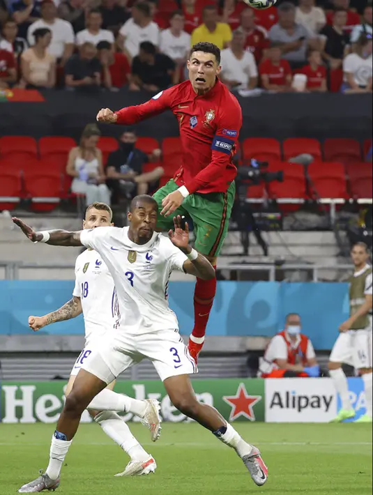 Pemain Portugal Cristiano Ronaldo menyundul bola di atas pemain Prancis Presnel Kimpembe pada pertandingan Grup F Euro 2020 di Puskas Arena, Budapest, Hungaria, Rabu (23/6/2021). Laga berakhir imbang 2-2. (Bernadett Szabo, Pool photo via AP)