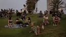 Orang-orang tanpa masker menyaksikan matahari terbenam, di Tel Aviv, Minggu (18/4/2021). Israel mencabut aturan wajib masker di ruang publik luar ruangan dan membuka kembali sekolah sepenuhnya dalam upaya menuju normalisasi setelah kampanye vaksinasi Covid-19 berjalan sukses. (AP Photo/Oded Balilty)