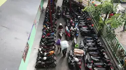 Pekerja memikul karung melintas di parkiran Blok G Tanah Abang, Jakarta, Jumat (27/4). Para pedagang menolak usul pemindahan buat pemugaran Blok G, karena beralasan pengunjung sepi jika mereka ditempatkan di Blok F. (Liputan6.com/Arya Manggala)