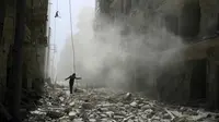 Seorang pria berjalan di antara reruntuhan bangunan setelah terjadi serangan udara di al-Qaterji dekat Aleppo, Suriah (25/9) (Reuters)