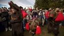 <p>Pengunjung datang dari berbagai penjuru dunia untuk menyaksikan pertunjukan ini, yang menampilkan barisan orang berkostum dengan rahang dan cakar beruang yang menganga berbaris dan menari. (AP Photo/Vadim Ghirda)</p>