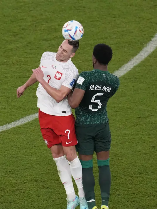 Penyerang Polandia,  Arkadiusz Milik berebut bola udara dengan pemain Arab Saudi, Ali Al-Bulaihi selama pertandingan grup C Piala Dunia 2022 Qatar di Education City Stadium di Al Rayyan, Qatar, Sabtu (26/11/2022). Kemenangan membuat Polandia kini memimpin Grup C Piala Dunia 2022. Lewandowski dkk kini mengoleksi 4 poin. (AP Photo/Themba Hadebe)