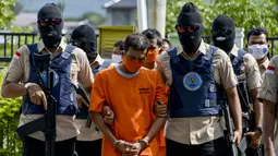 Petugas Badan Narkotika Nasional Indonesia (BNN) mengawal dua pria lokal yang diduga menyelundupkan sabu pada konferensi pers di Banda Aceh (13/10/2020). (AFP Photo/Chaideer Mahyuddin)