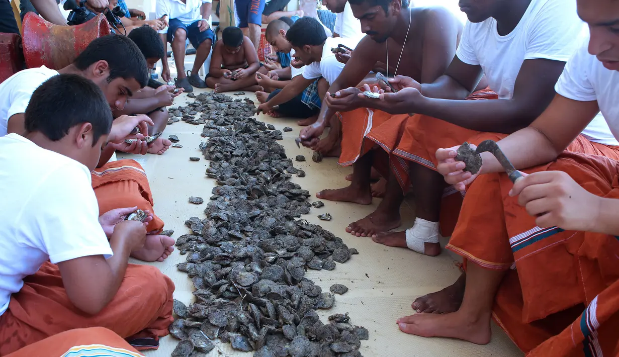 Sejumlah penyelam mengupas cangkang kerang yang sudah ditangkap selama musim berburu mutiara tahunan di lepas pantai kota pelabuhan Khairan, Kuwait (2/8). Warga Kuwait Berburu mutiara setiap tahun sekali. (AFP PHOTO/Yasser Al-Zayyat)