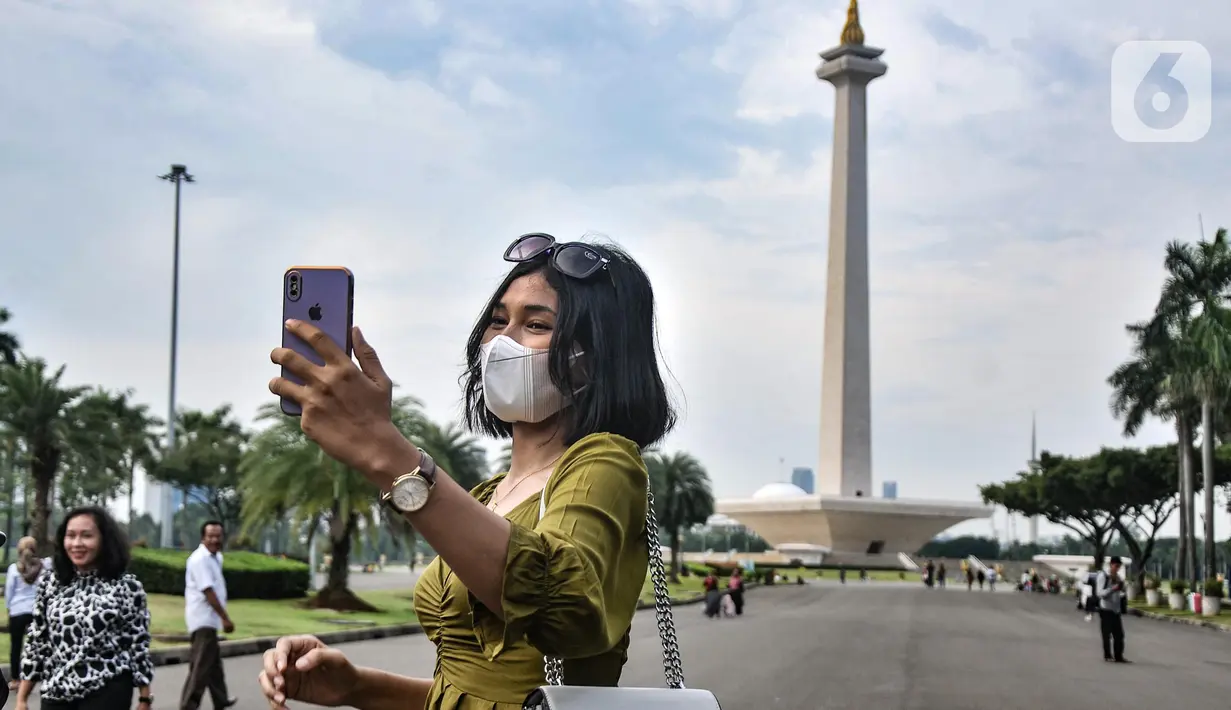 Warga berswafoto saat berkunjung pada hari perdana uji coba pembukaan Monumen Nasional (Monas), Jakarta Pusat, Kamis (16/6/2022). Pasca ditutup sejak 2020 akibat pandemi Covid-19, Pemprov DKI Jakarta melakukan uji coba pembukaan kawasan wisata Monas secara bertahap dan terbatas yang dimulai dari kawasan luar tugu. (merdeka.com/Iqbal S Nugroho)