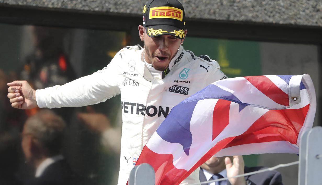 Pebalap F1 asal Inggris, Lewis Hamilton mengibarkan bendera negaranya usai menjuarai ajang Formula One Canadian Grand Prix di Montreal, Canada, (11/6/2017).  (Tom Boland/The Canadian Press via AP)