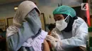 Seorang siswa menutup wajahnya saat disuntik vaksin COVID-19 Pfizer di SDN Panunggangan 5, Pinang, Kota Tangerang, Selasa (19/10/2021).  Pelaksanaan vaksinasi untuk pelajar usia 12 tahun ini dilakukan dalam rangka persiapan pelaksanaan pembelajaran tatap muka (PTM). (Liputan6.com/Angga Yuniar)