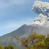 Asap bercampur abu vulkanis keluar dari kawah Gunung Agung terlihat dari desa Tulamben, Karangasem, Bali, Selasa (3/7). Pagi ini, Gunung Agung kembali meletus disertai abu vulkanik setinggi 2.000 meter di atas puncak. (AFP/SONNY TUMBELAKA)