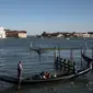 Seorang gondolier mendayung gondola di dekat gereja Santa Maria della Salute di Venesia pada 20 Mei 2021. Turis kembali berdatangan menikmati keindahan Venesia, yang sering dijuluki kota paling romantis di dunia, setelah Italia menghapus kewajiban karantina bagi pendatang. (Marco Bertorello/AFP)