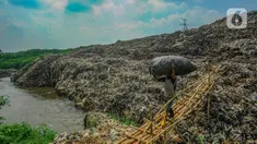 Warga membawa sampah daur ulang melewati lokasi longsor Tempat Pembuangan Akhir (TPA) Cipayung yang menimbun Kali Pesanggrahan di Depok, Jawa Barat, Selasa (30/4/2024). (merdeka.com/Arie Basuki)