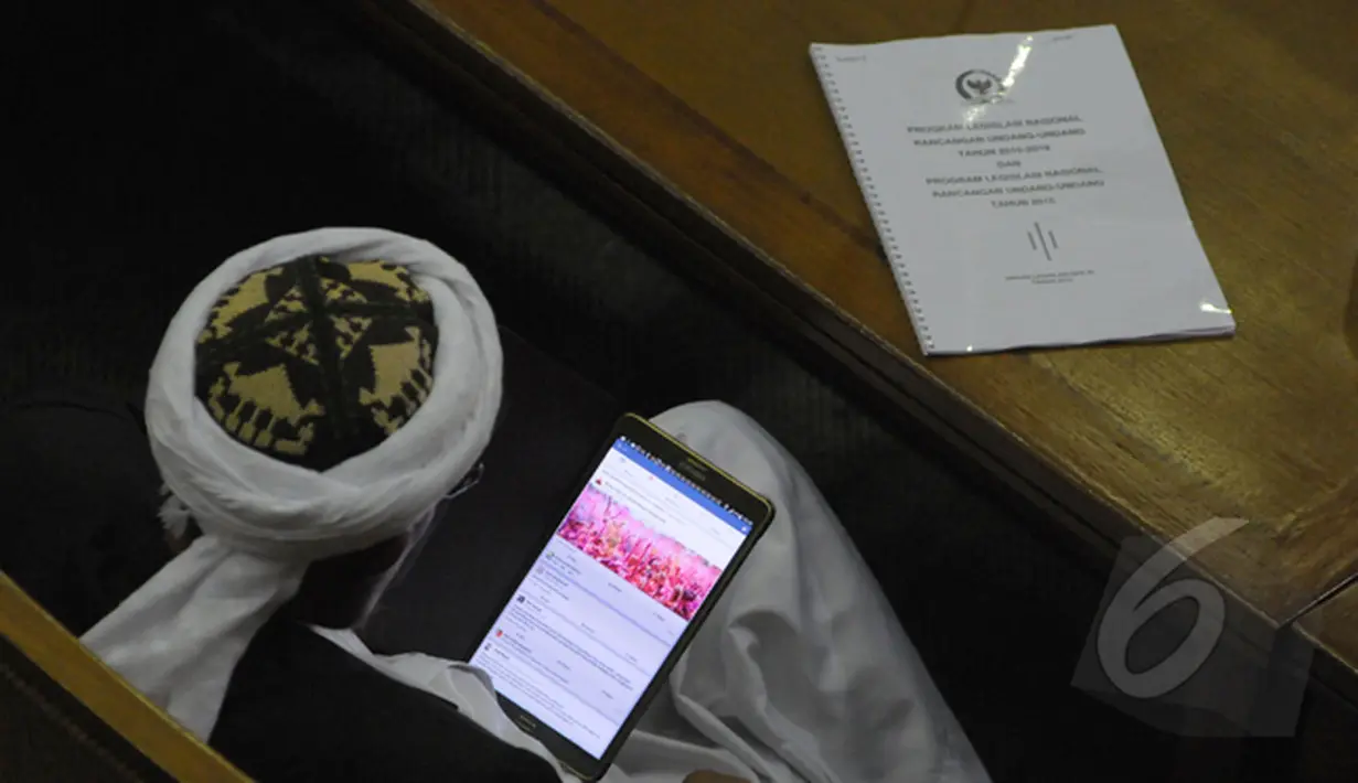 Saat rapat Paripurna sejumlah anggota dewan sibuk dengan ponselnya.Tampak seorang anggota dewan sedang melihat situs jejaring sosial saat rapat Paripurna DPR, Jakarta (09/02/2015). (Liputan6.com/Andrian M Tunay)