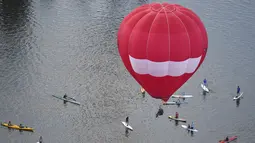 Para pedayung saat melihat balon udara yang terbang diatas danau Burley Griffin, Canberra,  Australia, (15/3). Ini dilakukan dilakukan dalam memperingati ulang tahun ke-30 festival Balloon Spectacular Canberra . (REUTERS / Lukas Coch)