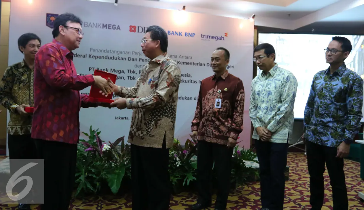 Mendagri Tjahjo Kumolo mendapat cendera mata dari Dirut PT Bank Mega Kostaman Thayib saat melakukan perjanjian kerja sama pemanfaatan no induk kependudukan, data kependudukan dan E KTP di Jakarta, Selasa (20/9). (Liputan6.com/Angga Yuniar)