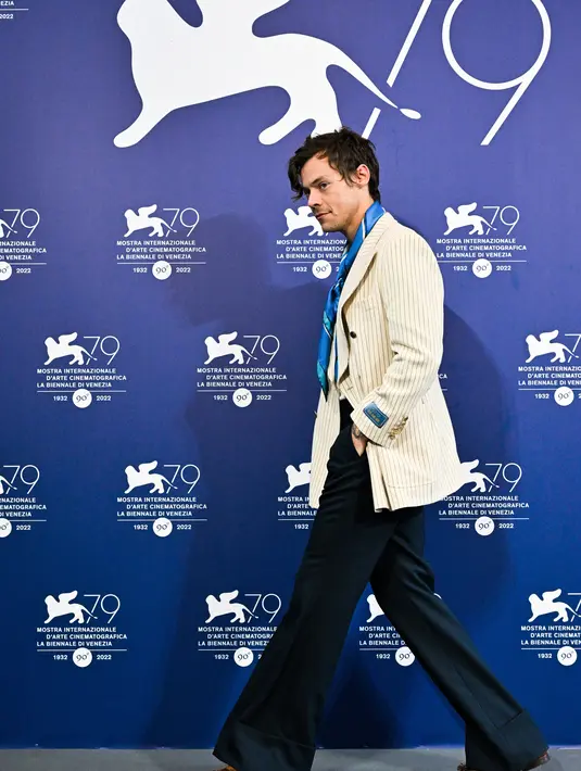 <p>Penyanyi dan aktor Inggris Harry Styles tiba untuk berpose selama sesi pemotretan untuk film "Don't Worry Darling" selama Venice Film Festival 2022 ke-79 di Venesia, Italia (5/9/2022). Harry Styles tampil mengenakan blazer krem bergaris-garis dengan celana panjang hitam longgar dan dasi biru. (AFP/Tiziana Fabi)</p>