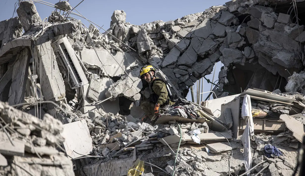 Petugas tanggap darurat Israel memeriksa sebuah lokasi yang terkena rudal yang ditembakkan dari Iran di selatan Tel Aviv pada 14 Juni 2025. (JOHN WESSELS/AFP)