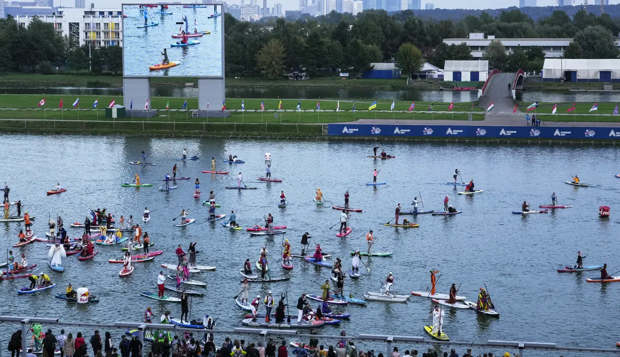 Orang-orang berdiri di atas papan SUP selama festival dayung berdiri (stand up paddle) di kanal dayung Olimpiade Krylatskoye, Moskow, Rusia, Minggu (12/9/2021). Selain menjadi agenda rutin pariwisata, kegiatan tersebut juga dimaksud untuk memopulerkan SUP ke masyarakat luas. (AP/Pavel Golovkin)