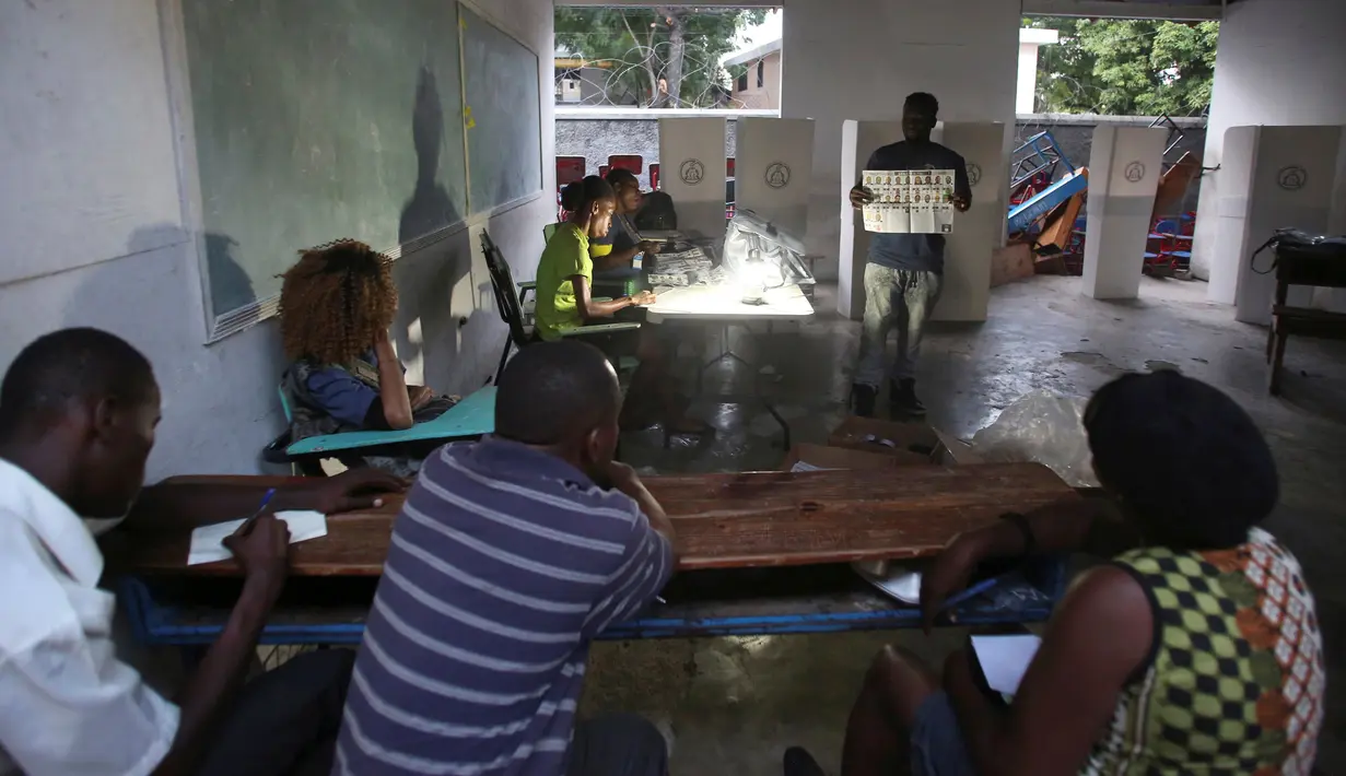 Petugas pemilu menunjukan gambar surat suara saat berlangsungnya pemilu  di Port-au-Prince, Haiti (20/11). Pemilihan umum ini sempat tertunda pada bulan Oktober lalu akibat badai Matthew yang melanda Haiti. (Reuters/Jeanty Junior Augustin) 