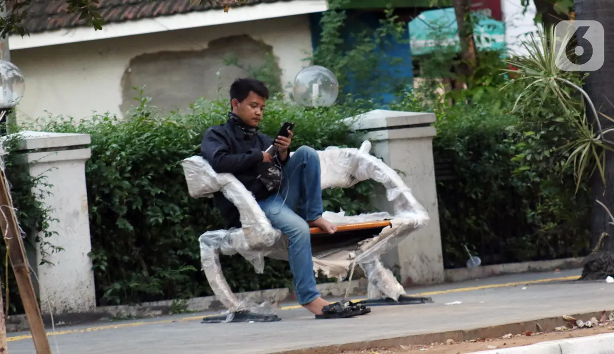 Warga duduk di bangku taman di trotoar Jalan Cikini Raya, Jakarta, Minggu (8/12/2019). Sebagai bagian dari proyek revitalisasi, kini sepanjang trotoar Cikini Raya mulai terpasang bangku-bangku taman. (Liputan6.com/Helmi Fithriansyah)