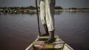 Seorang pemandu wisata mendorong tongkangnya melewati perairan merah muda Danau Retba (Danau Merah Muda) di Senegal pada 16 Maret 2021. Selayaknya air dengan kandungan garam pekat, orang-orang pun tidak akan bisa berenang di sana karena akan mengambang di permukaan danau. (MARCO LONGARI/AFP)