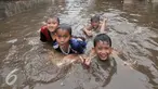 Sejumlah anak di kawasan Kemang Utara memanfaatkan banjir untuk bermain, Jakarta, Rabu (20/7). Akibat intensitas hujan deras yang mengguyur Jakarta, sejumlah ruas jalan tergenang air. (Liputan6.com/Yoppy Renato)