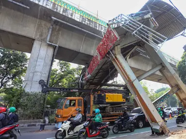 Sebuah truk truk towing pengangkut alat berat (crane) tersangkut dan merusak jembatan penyeberangan orang (JPO) di Jalan Raya Kapten Tendean, Jakarta, Selasa (14/07/2026).