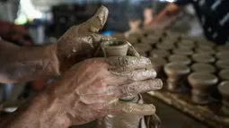 Seorang pria menggunakan roda tembikar untuk membentuk bejana tanah liat di salah satu bengkel tembikar tertua di Beit Lahia, Jalur Gaza, 15 Agustus 2022. Bejana 'al-Qedra' biasa digunakan untuk memasak makanan tradisional Gaza yang terbuat dari nasi, daging, bawang putih, dan bawang. (AP Photo/Hatem Moussa)