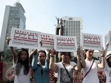 Sejumlah peserta memegang poster disela kegiatan car free day di Bundaran HI, Jakarta, Minggu (8/5). Aksi itu merupakan solidaritas serta bentuk kecaman terhadap kekerasan seksual yang menimpa pelajar asal Bengkulu Yuyun (14). (Liputan6.com/Faizal Fanani)