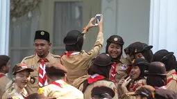 Seorang wanita dari delegasi gerakan Pramuka Indonesia tampak berselfie ria di Halaman Istana Merdeka, Jakarta, Jumat (24/7/2015). Presiden Jokowi juga menghadiri acara pelepasan 462 kontingen Pramuka Indonesia ke jepang. (Liputan6.com/Faizal Fanani)