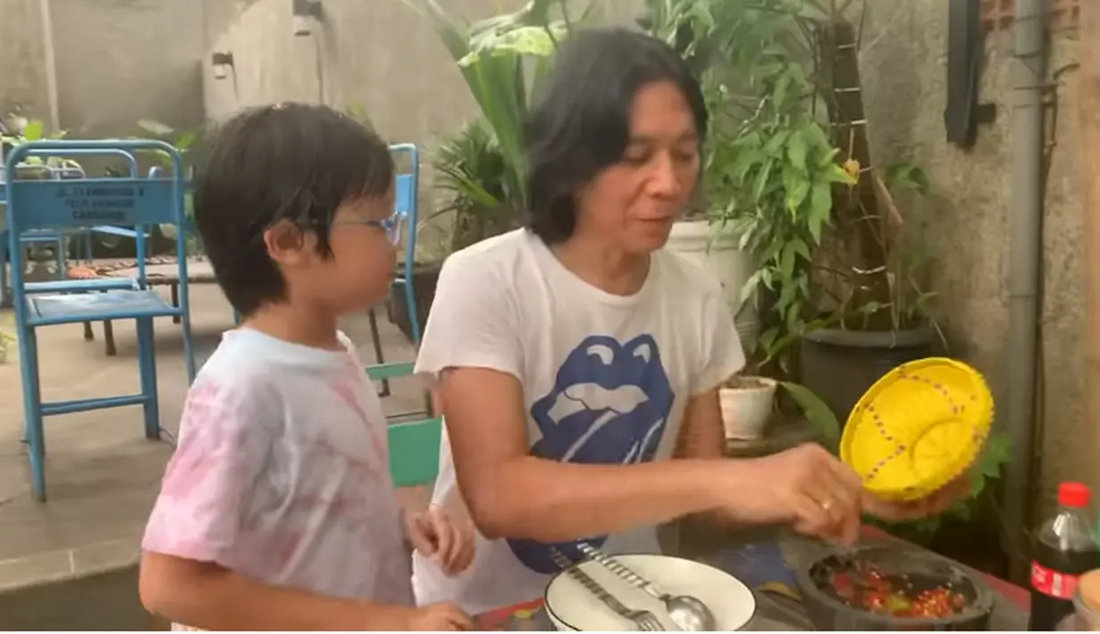 Sebelumnya, pentolan grup yang berdiri sejak tahun 1983 itu terlebih dulu mengambil petai cina yang masih muda. Pria tiga orang anak itu tampak mengajari anak ketiganya cara lalap petai cina dengan sambal. [Youtube/ALZ Family Bimbim Slank]