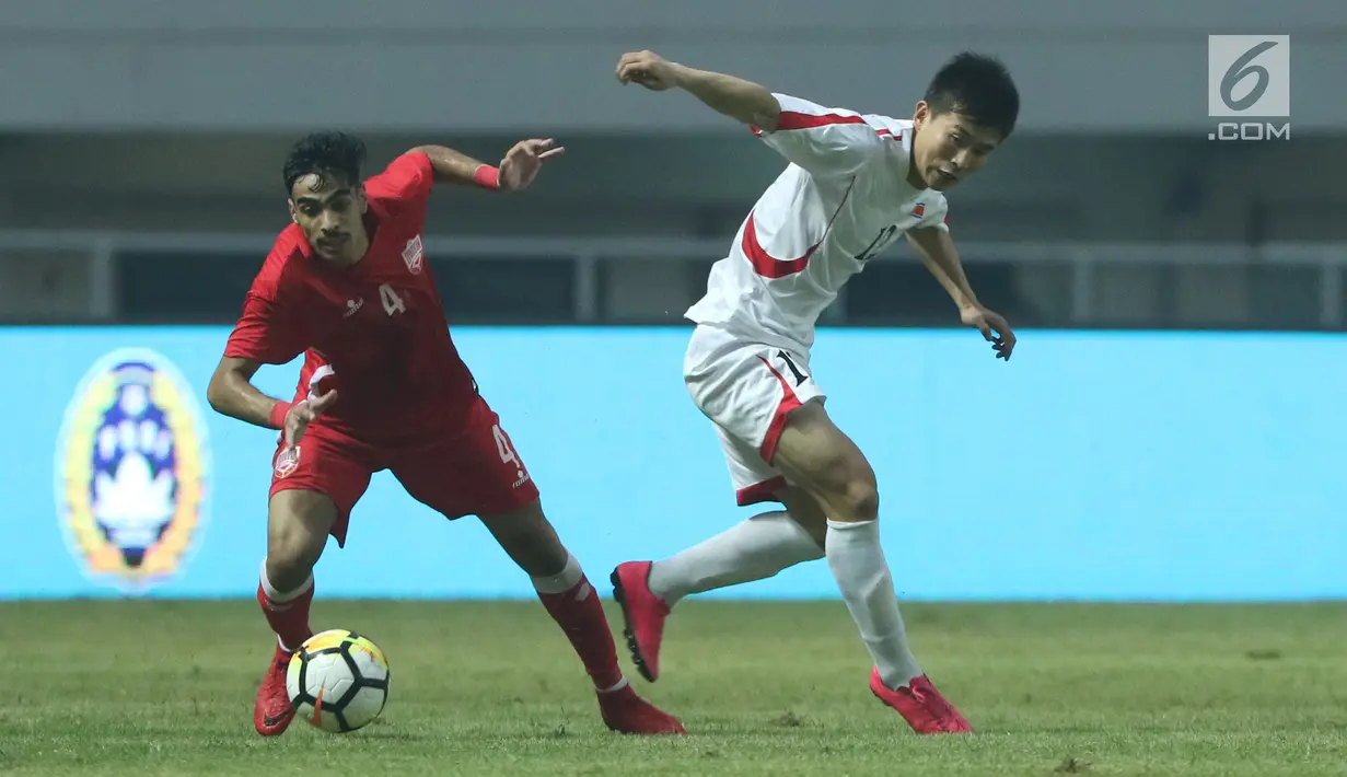 Pemain belakang Bahrain, Husain Sabba (kiri) berebut bola dengan bek Korea Utara, O Chol Hyok pada laga PSSI Anniversary Cup 2018 di Stadion Pakansari, Kab Bogor, Kamis (3/5). Laga dimenangkan Bahrain 4-1. (Liputan6.com/Helmi Fithriansyah)