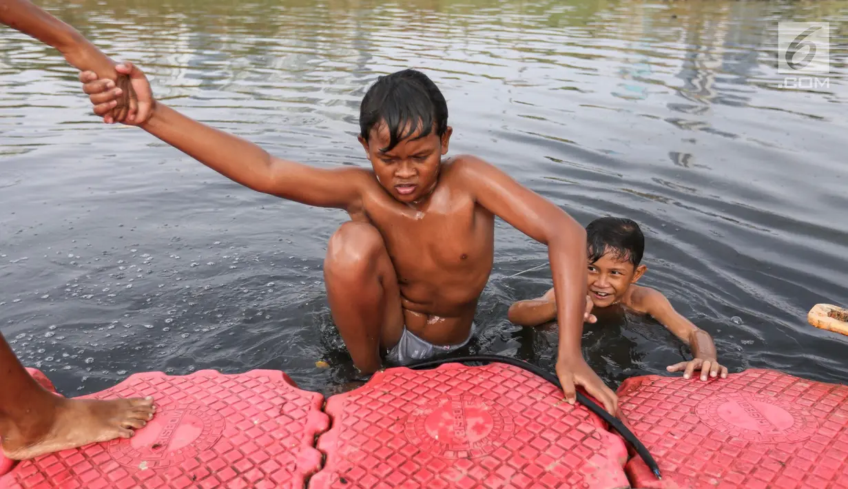 Anak-anak berenang di Kanal Banjir Barat (KBB) di Petamburan, Jakarta, Senin (12/8/2019). Anak-anak memanfaatkan waktu pulang sekolah mereka untuk berenang dan mencari ikan di KBB saat musim kemarau. (Liputan6.com/Fery Pradolo)