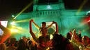 Foto kombinasi menunjukkan segelintir orang di depan Gerbang India yang ikonik, atas, tempat populer untuk merayakan Malam Tahun Baru di Mumbai, India, Kamis, 31 Desember 2020, dibandingkan dengan file foto kerumunan yang merayakan pada 31 Desember 2019. (AP Photo/Rafiq Maqbool, Rajanish Kakade)