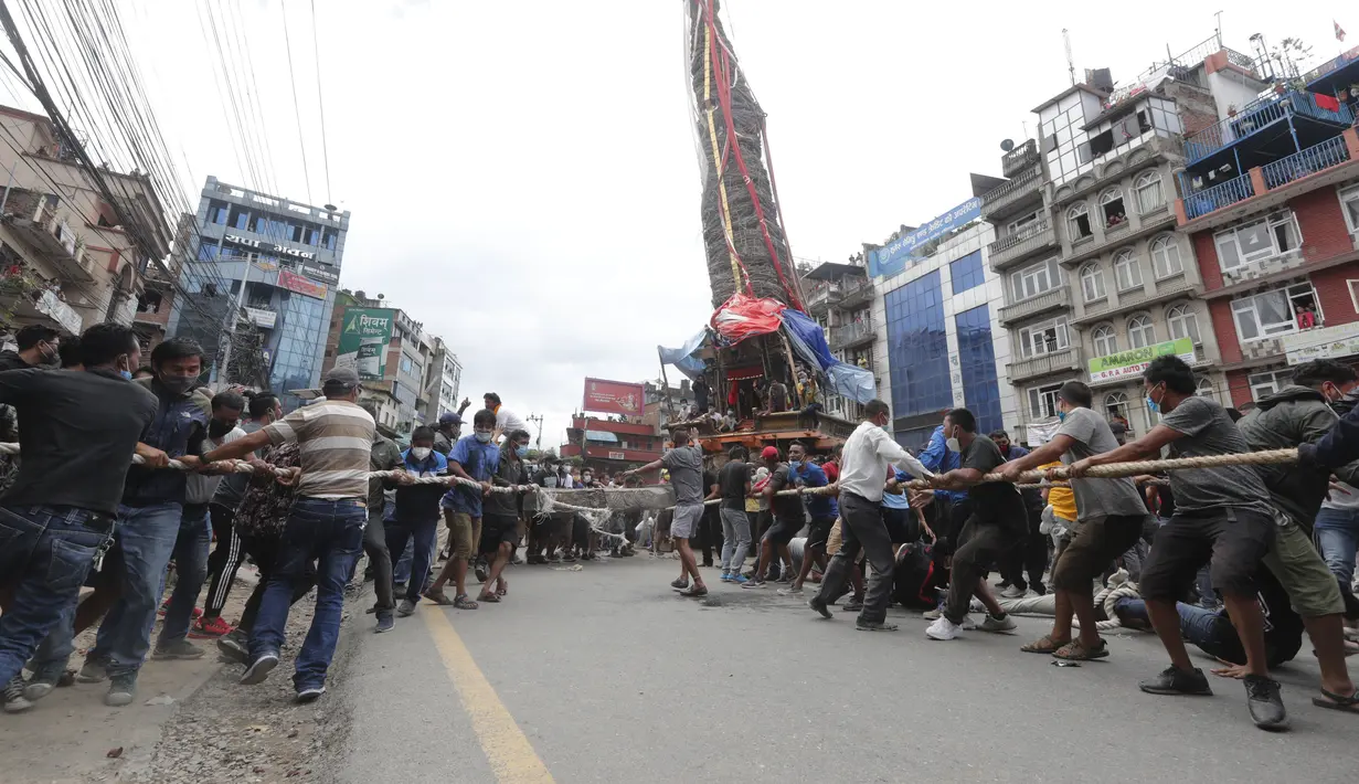Warga Nepal menarik kereta Dewa Rato Machhindranath dalam sebuah festival keagamaan di Lalitpur, Nepal (3/9/2020). Petugas polisi dengan perlengkapan anti huru hara memblokir para pengunjuk rasa ketika mereka memindahkan kereta, menyiram mereka dengan meriam air. (AP Photo/Niranjan Shrestha)