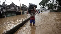 Warga berjalan melintasi banjir membawa barang mereka di Jalan Jatinegara Barat, Jakarta Timur, Selasa (6/2). Akibat banjir ini ruas jalan tersebut tidak dapat dilalui kendaraan. (Liputan6.com/Arya Manggala)