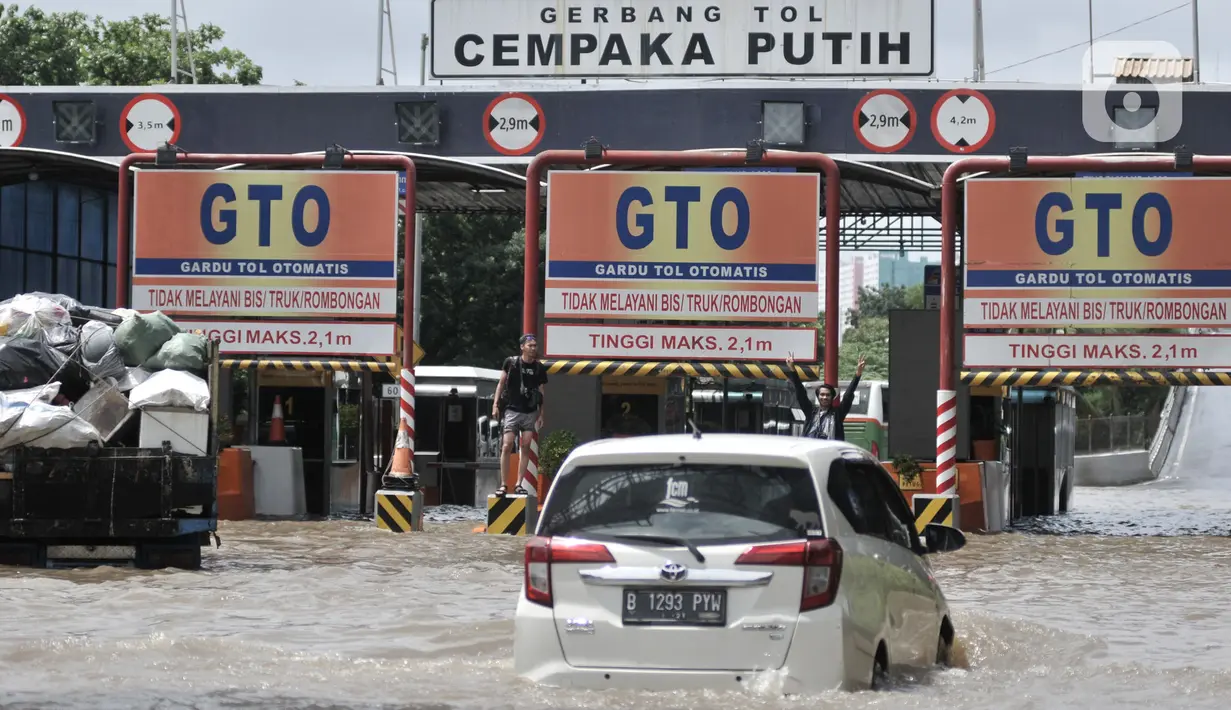 Mobil nekat menerobos banjir menuju Gerbang Tol Cempaka Putih, Jakarta, Minggu (23/2/2020). Banjir yang melanda kawasan tersebut menyebabkan Gerbang Tol Cempaka Putih tidak dioperasikan akibat terendam hingga ketinggian mencapai sepinggang orang dewasa. (merdeka.com/Iqbal S. Nugroho)