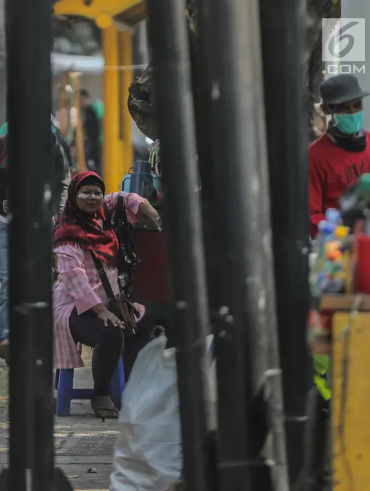 Pedagang menggunakan odol diwajah menghindari sisa gas air mata pasca bentrok massa dengan aparat di Palmerah, Jakarta, Kamis (26/9/2019). Banyak masyarakat yang melintas dan warga sekitar perih pada mata hingga bersin akibat sisa gas air mata pasca bentrokan kemarin. (Liputan6.com/Faizal Fanani)