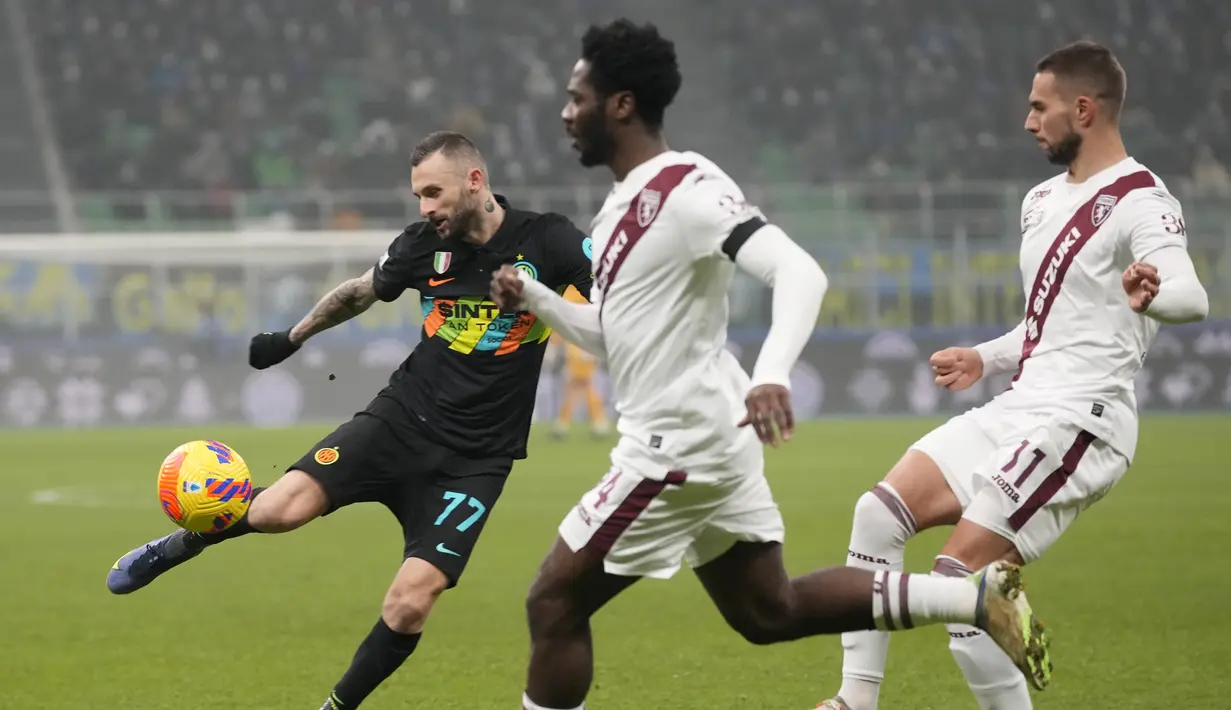 Gelandang Inter Milan, Marcelo Brozovic menendang bola dari kawalan pemain Torino, Ola Aina dan Marko Pjaca pada pertandingan Liga Serie A Italia di Stadion San Siro, di Milan, Italia, Kamis (23/12/2021). Hasil ini membuat Inter tetap berada di puncak klasemen dengan koleksi 44 poin. (AP Photo/Luca