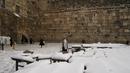 Seorang pria Yahudi ultra-Ortodoks berdiri di atas salju sambil berdoa di Tembok Barat, situs paling suci di mana orang Yahudi dapat berdoa di kota tua Yerusalem, Kamis (27/1/2022). Hujan salju yang jarang melanda sebagian wilayah Israel dan Tepi Barat, menutup sekolah dan bisnis. (AP Photo/Mahmoud
