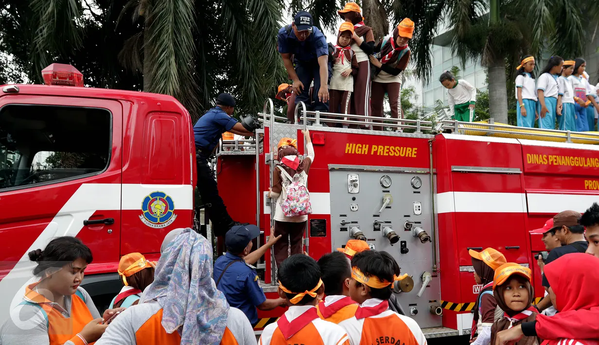 Petugas membantu anak-anak peserta acara Madrasah Siaga Bencana menaiki mobil pemadam kebakaran di hari bebas kendaraan bermotor di kawasan Thamrin, Jakarta, Minggu (22/1). (Liputan6.com/Johan Tallo)