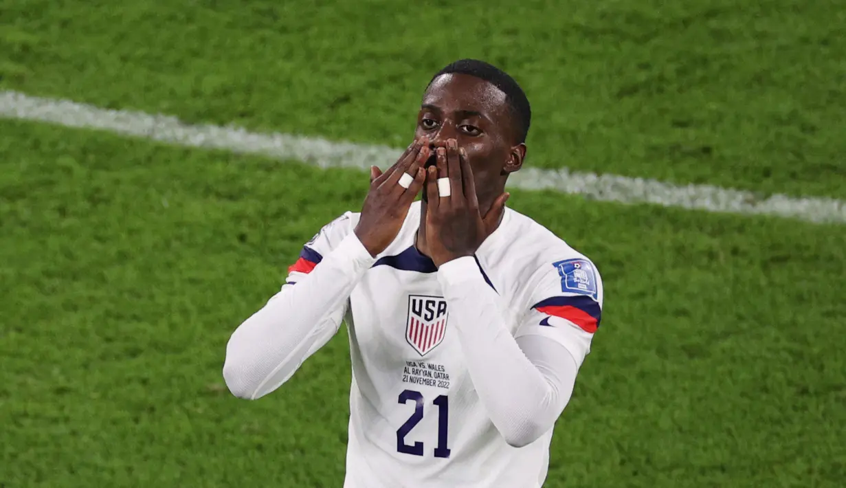 <p>Penyerang Timnas Amerika Serikat Timothy Weah melakukan selebrasi setelah mencetak gol pertama timnya pada pertandingan sepak bola Grup B Piala Dunia Qatar 2022 antara Amerika Serikat dan Wales di Stadion Ahmad Bin Ali di Al-Rayyan, Doha, Qatar, Senin (21/11/2022). Meski baru berusia 22 tahun, Weah Jr termasuk dalam sederet striker muda terbaik AS yang telah mengantongi 25 caps sejak debut di 2018. (ADRIAN DENNIS/AFP)</p>