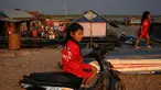 Seorang anak menaiki motor saat bermain di dekat desa terapung di sepanjang sungai Siem Reap, Kamboja (5/12/2019). Sungai Siem Reap adalah sungai yang mengalir melalui Provinsi Siem Reap, di barat laut Kamboja. (AFP/Manan Vatsyayana)