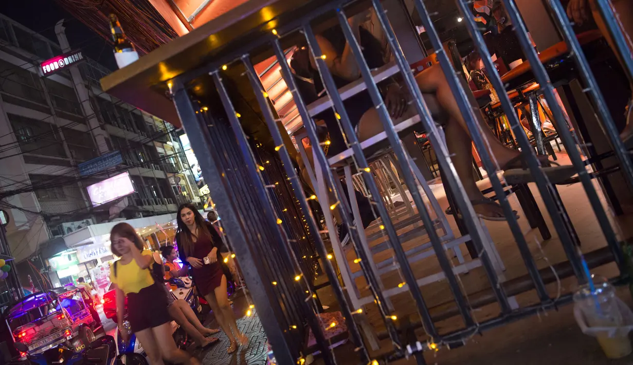 Foto pada 11 Oktober 2018 memperlihatkan wanita berjalan melewati sebuah bar di Nana Red Light Distrik, Bangkok, Thailand. Kawasan tersebut merupakan tempat lokalisasi hiburan malam paling tersohor di Bangkok. (Romeo GACAD / AFP)