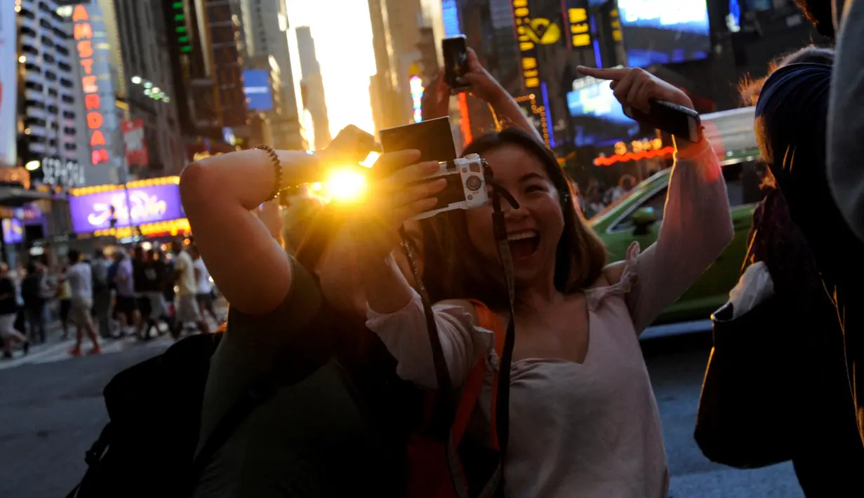 Wisatawan berselfie saat terjadi Manhattanhenge di New York, AS, Senin (11/7). Manhattanhenge adalah saat dimana matahari terbit dan terbenam dalam garis lurus di jalan utama Manhattan. (REUTERS)