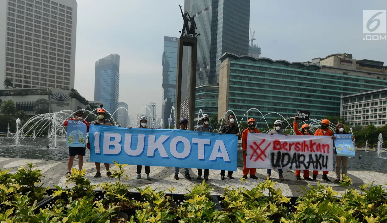 Aktivis dari Gerakan Inisiatif Bersihkan Udara Koalisi Semesta (Ibu Kota)membentangkan spanduk saat melakukan kampanye damai terkait buruknya udara Jakarta di Bundaran HI, Jakarta, Rabu (5/12). (Merdeka.com/Imam Buhori)