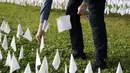 Relawan memancangkan bendera putih ke instalasi seni sementara untuk mengenang warga Amerika yang meninggal karena COVID-19 di dekat Stadion RFK di Washington, Selasa (27/10/2020). Instalasi seni Suzanne Brennan Firstenberg itu disebut "In America, How Could This Happen.” (AP/Patrick Semansky)