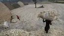 Pekerja membawa serat tebu setelah mengekstrak sarinya untuk membuat gula merah di pinggiran Bareilly, India, Selasa (23/3/2021).  Jaggery adalah gula tradisional yang tidak dimurnikan yang dikonsumsi di banyak bagian Asia, terbuat dari molase tebu dan nira kurma. (AP Photo/Rajesh Kumar Singh)