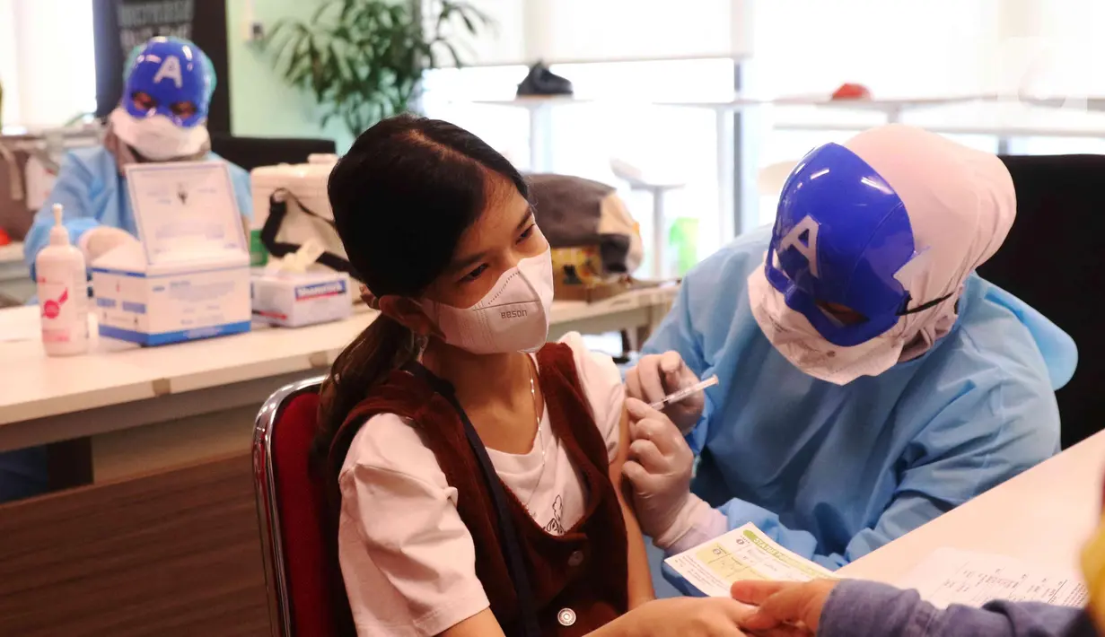 Petugas medis dengan mengenakan topeng superhero menyuntikkan vaksin Sinonvac kepada anak-anak saat mengikuti vaksinasi kedua di Gedung  Otoritas Jasa Keuangan (OJK), Jakarta, Minggu (16/01/2022). (Liputan6.com/Angga Yuniar)
